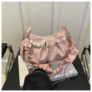 Detalle de bolso medialuna rosa plisado con cadena de perlas y flores decorativas