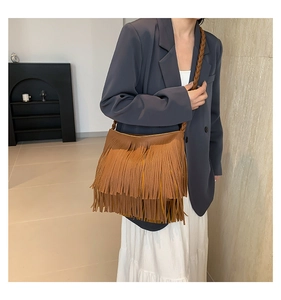 Detalle de bolso marrón con flecos escalonados y correa trenzada estilo bohemio
