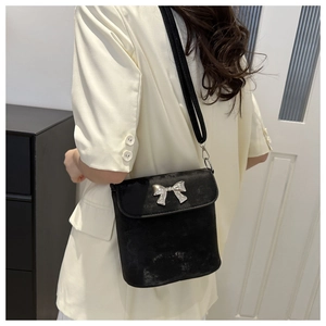 Detalle de bolso tipo cubo negro con hebilla de lazo plateado y textura mate de calidad
