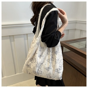 Détail d'un sac cabas blanc avec imprimés papillons gris et bords à franges effilés