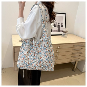Détail du sac cabas en dentelle florale avec motifs bleus et orange sur tissu canevas