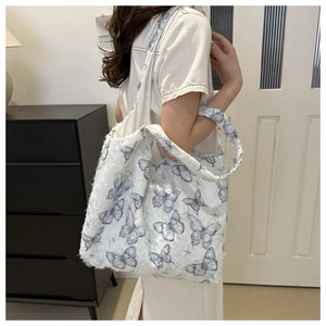 Détail d'un grand cabas avec imprimé papillon bleu sur une texture en fausse fourrure blanche