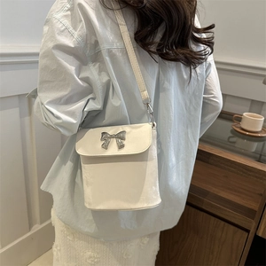 Bolso bandolera de terciopelo blanco con lazo de metal plateado mostrado en modelo