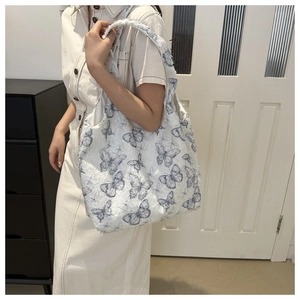 Détail du sac cabas en peluche blanche avec motifs de papillons bleus et texture douce