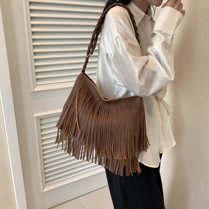 Bolso hobo grande de cuero marrón oscuro con flecos y correa trenzada en una modelo