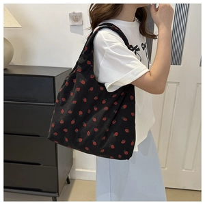 Detailed texture of black corduroy tote bag featuring vibrant red strawberry patterns