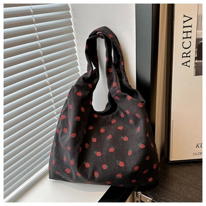 Close-up of black corduroy tote bag featuring red strawberry patterns and soft texture