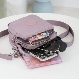 Bolso bandolera de nailon morado con tres compartimentos y correa ajustable