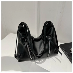 Detail of black soft leather hobo bag featuring silver zippers and long tassel accents