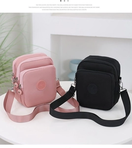 Vista detallada de bolsos bandolera de nailon rosa y negro con compartimentos con cremallera