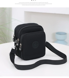 Detalle de tres compartimentos con cremallera en un bolso bandolera de nailon negro