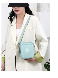 Detalle de bolso bandolera de nailon verde menta con correa ajustable en una modelo