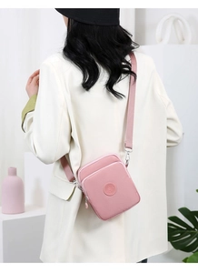 Bolso bandolera rosa de nailon impermeable lucido por una modelo en un entorno urbano