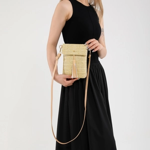 Detail of straw woven mini crossbody bag featuring a long tassel and slim shoulder strap