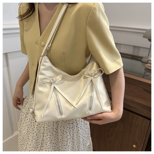 Borsa a tracolla crema minimalista con fiocchi e cerniere metalliche indossata da modella