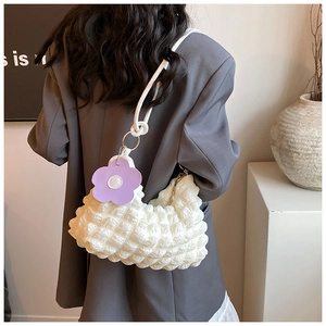 Close-up of a white popcorn textured shoulder bag with a purple flower charm detail