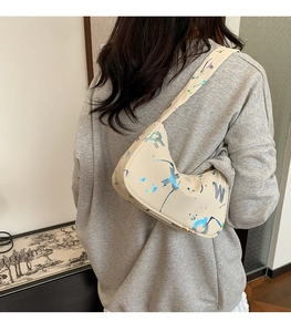 Detail of beige underarm bag with laser graffiti letters and colorful paint splatters