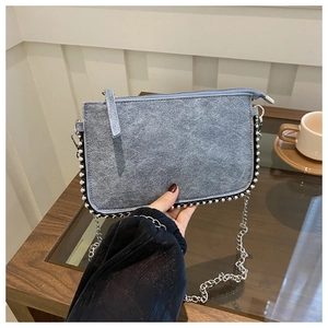 Detailansicht einer graublauen Wildledertasche mit Silberperlenverzierung und Kette