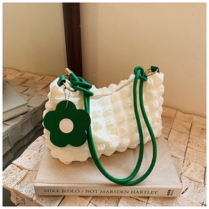 Detail of white bubble fabric shoulder bag with green knotted strap and floral charm