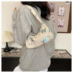 Detail of hobo bag with blue metallic lettering and graffiti pattern on creamy leather