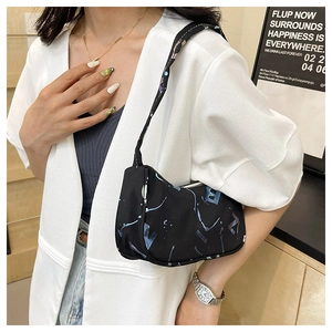 Close-up of black floral baguette bag with blue abstract patterns and slender shoulder strap