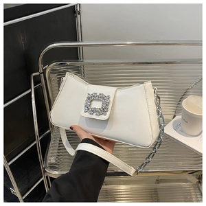 Detailed close-up of white baguette bag featuring a sparkling square rhinestone buckle