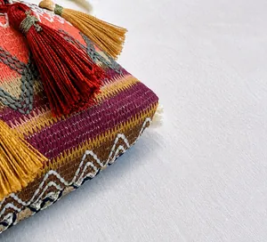 Dettaglio di borsa a secchiello etnica colorata con motivi intrecciati e frange morbide