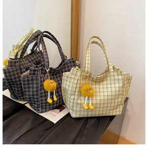 Detail of tweed checkered tote bags featuring fuzzy yellow charms and woven texture