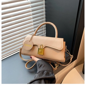 Detailed view of beige handbag with gold padlock clasp and fashion charm on desktop