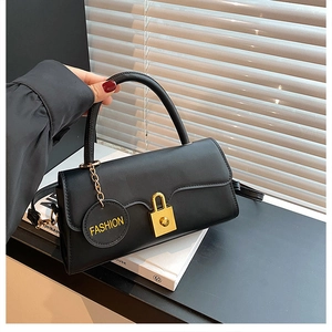 Detail of black leather handbag with gold lock and Fashion charm in natural light