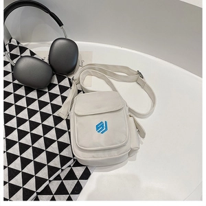 Detail of white canvas crossbody bag featuring blue logo and side pocket in workwear style