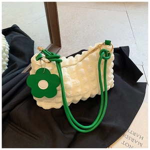 Detail of white bubble texture bag with green rope strap and floral pendant charm
