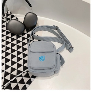 Close-up of gray-blue canvas shoulder bag with geometric logo and adjustable strap