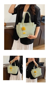 Detail of green checkered knit tote bag featuring a cute plush toy charm and top handle