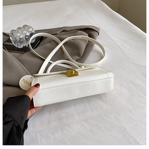 Detail of white leather shoulder bag featuring a gold square lock and decorative logo tag