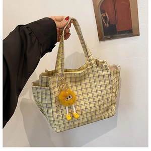 Close-up of yellow plaid knit tote bag with a cute plush monster charm and side pocket