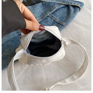 Detail view of the interior compartment and silver zipper of this white utility crossbody bag