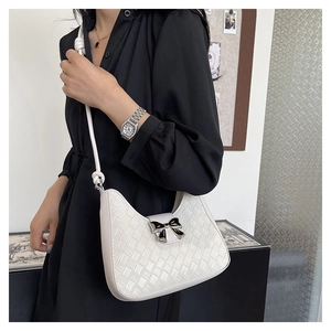 Close-up of white woven leather crescent bag featuring a stylish black bow detail