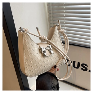 Detail of cream woven shoulder bag with silver bow buckle and wide leather strips