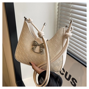 Close-up of cream woven leather shoulder bag featuring a silver metal bow buckle detail