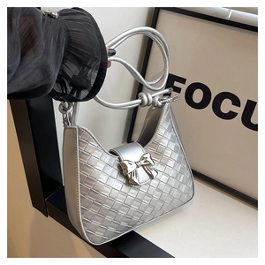 Detail of silver woven crescent bag featuring a metallic bow and elegant rope strap