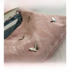 Macro detail of pink bag showing unique ruched texture and silver metal butterfly charms