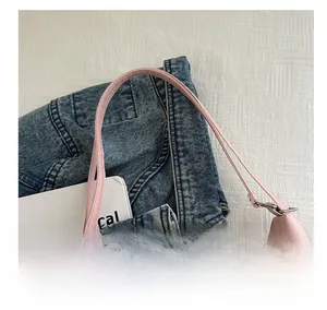 Detail of the pale pink glossy shoulder bag featuring slim straps and a smooth metallic zipper