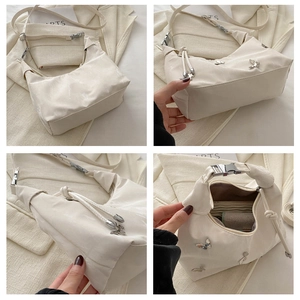Detail view of cream crescent bag with silver butterfly charms and buckle strap