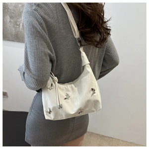 Detail of white PU leather underarm bag featuring decorative silver metal butterflies
