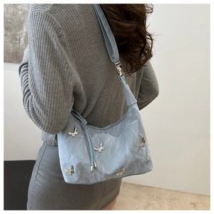 Detail of light blue crossbody bag with silver butterfly charms and adjustable strap