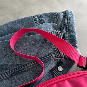Detalle de bolso de tela oxford rosa con correa ancha tejida y cremallera metálica