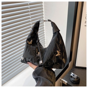 Detail of black crescent hobo bag with pleated texture and silver butterfly charms