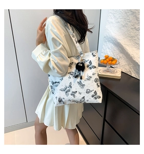 Detailopname van witte vlinder-tote bag met een schattige roetmannetje pluche hanger