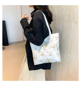 Detail van witte shopper met gouden vlinders en astrologische patronen op gladde stof